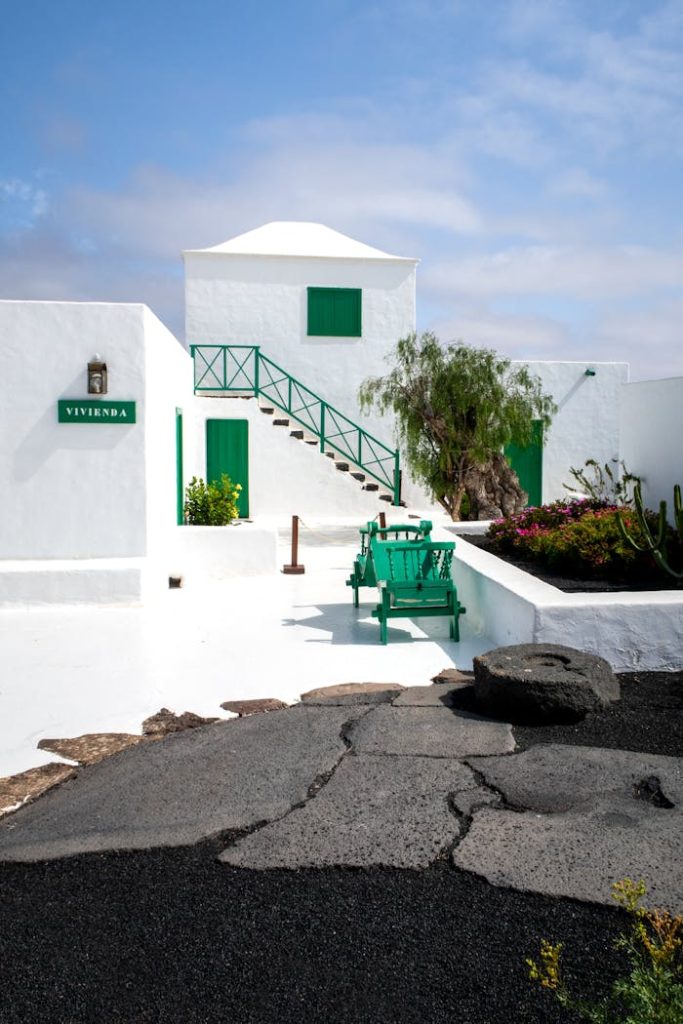 Beautiful white villa in Lanzarote, Spain, with vibrant green accents, under a sunny sky.