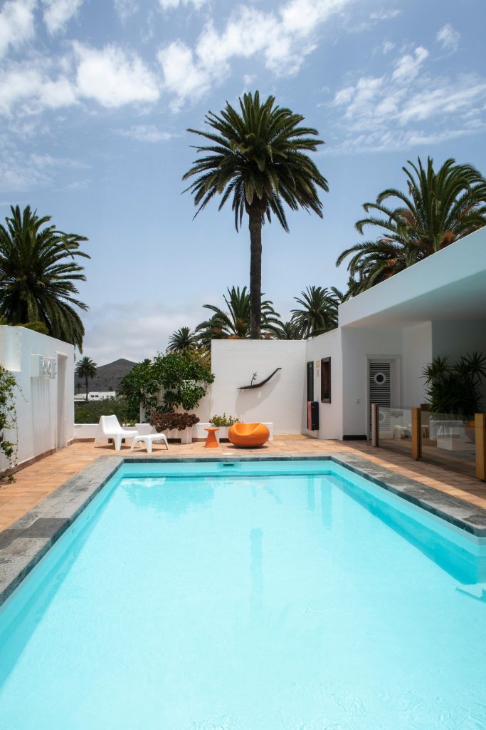 Serene outdoor pool area with palm trees under a bright sky in Lanzarote, Spain.